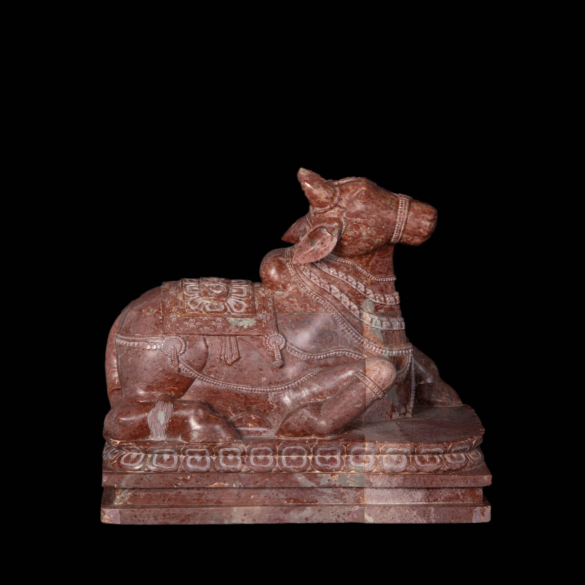 Red carved marble sculpture of a seated bull